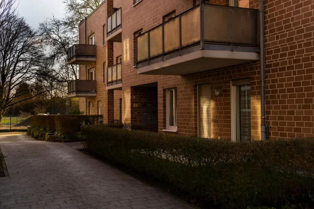 Mehrfamilienhaus aus rotem Backstein mit Balkonen und Zufahrt