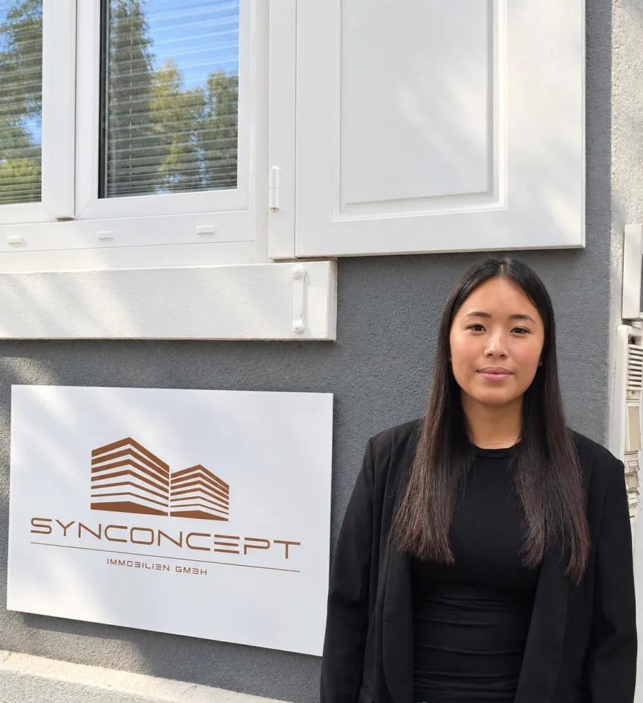 Hong Hanh Nguyen, Property Managerin, vor dem SynConcept Firmenschild